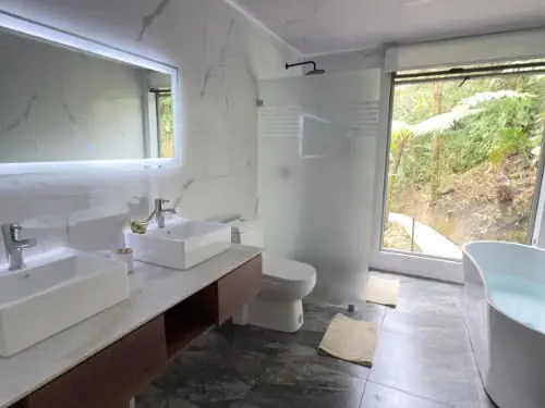 Spacious bathroom with double sink, soaking tub, and shower, with large window for natural light at Mashpi Amagusa Guest House