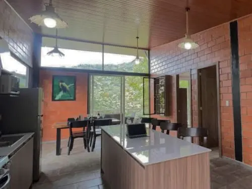 Open kitchen in Mashpi Amagusa Guest House with bar seating, full appliances, dining area with large window views of the cloud forest