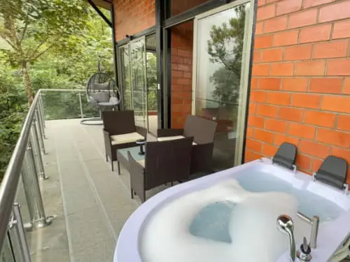 Private balcony at Mashpi Amagusa Guest House with seating area and jacuzzi tub overlooking the cloud forest